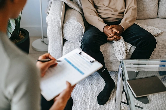A clinician taking notes during a session with a patient